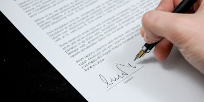 Eine Hand unterschreibt einen Vertrag.